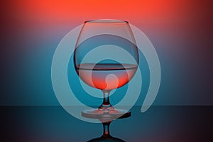 Abstract colored cognac glass on orange blue background