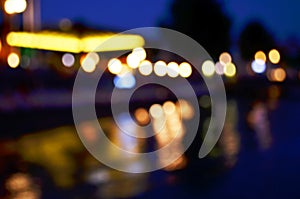Abstract colorful bokeh effect city lights reflected over night water outdoor background.