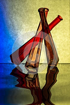 Abstract composition of colored glass bottles on reflective surface