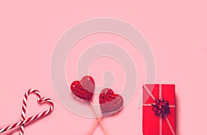 Abstract composition with two decorative hearts, lollipops and red present box on pink paper background. Valentine day theme. Love