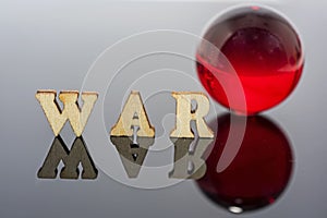 Abstract composition of war. Isolated wooden letters and red glass ball