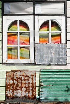 Abstract composition with wooden rounded windows, rusty metal plate and colored curtains with sun light