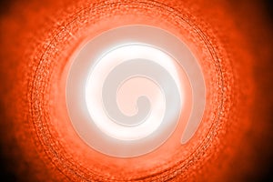 Abstract concentric background pattern in bright orange color with a sun halo in the center