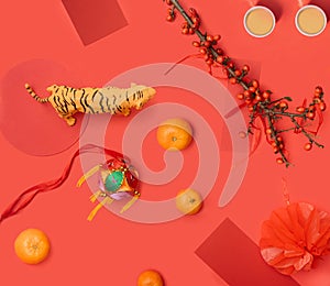 Abstract concept of Chinese new year celebration. Tiger toy, pomegranate, branch with red berries, red cards and two cups of tea,