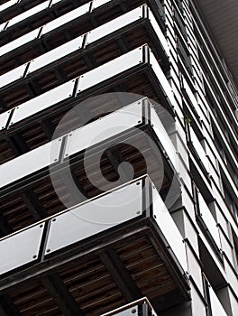 Abstract corner view of a tall modern urban apartment building with black cladding and glass balconies