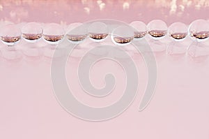 Abstract cosmetic festive background -  glass nucleuses with gold glitter on pastel pink backdrop, copy space.