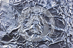 Abstract crumpled silver aluminum foil closeup background texture, detailed pattern in blue