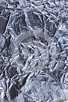 Abstract crumpled textured silver aluminum foil, large detailed vertical background closeup texture pattern in blue