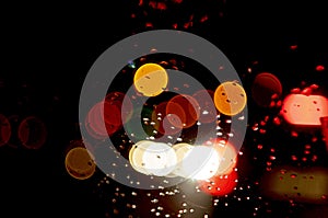 Abstract dark background with colorful bokeh and water drops. Car glass in rainy weather
