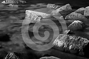 Abstract, dark, organic background, scattered rocks immersed in sea water .