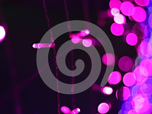 Abstract Dark Pink Bokeh light blurred background, lightbulb on Christmas tree for celebrate season with pink purple and colorful