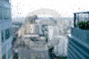 Abstract defocused background of city in rain, raindrops on window glass