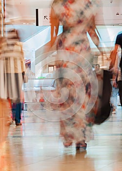 Abstract defocused motion blurred young people walking in the shopping center. Beautiful figure of a girl close-up