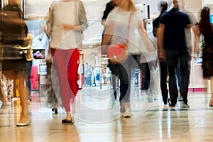 Abstract defocused motion blurred young people walking in the shopping center, urban lifestyle concept. For background