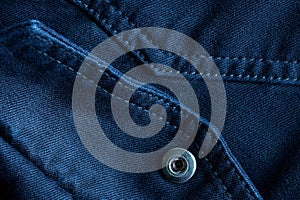 Abstract denim background with button fastening and decorative stitches. Stitching with thread