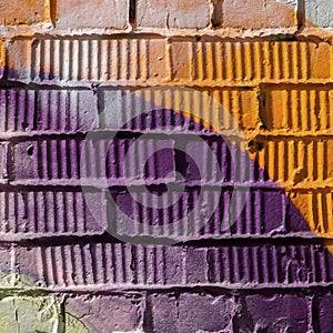 Abstract detail of brick wall with fragment of violet and orange graffiti. Urban Art close-up, for background use