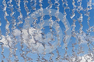 Abstract detail of water falling from a fountain against a blue sky