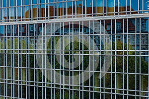 Abstract distorted reflection of historic house and green trees in mirrored glass wall of modern corporate building