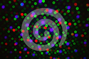 Abstract dot defocus background backdrop, rainbow colored green red violet round glitter on black background. Illumination blurry