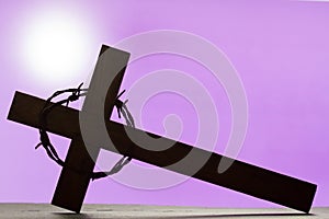 Abstract easter wooden cross and crown of thorns on purple background
