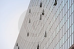 abstract facade of a finance business building with mirror windows, some of them being opened to let air inside the office.