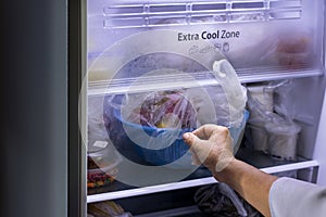 Abstract female hand of woman is opening a gray refrigerator door