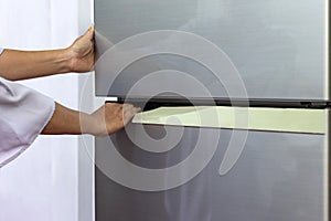 Abstract female hand of woman is opening a gray refrigerator door