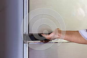 Abstract female hand of woman is opening a gray refrigerator door