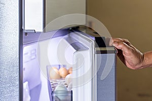 Abstract female hand of woman is opening a gray refrigerator door