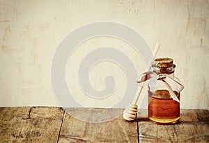 Abstract filtered image of honey glass jar. rosh hashanah (jewesh holiday) concept. traditional holiday symbols.