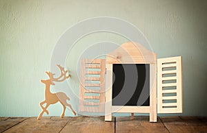 Abstract filtered photo of decorative chalkboard frame and wooden deer over wooden table. ready for text or mockup