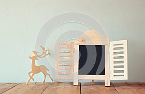 Abstract filtered photo of decorative chalkboard frame and wooden deer over wooden table. ready for text or mockup