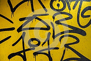 Abstract fragment of creative black scribble on yellow painted concrete wall. Modern background