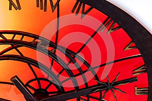 An abstract fragment of a decorative brass clockwork on a shiny red-orange background.