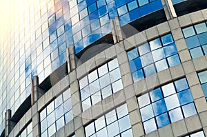 Abstract fragment of a modern building with glass facade for offices. Sky and clouds reflected on the glass