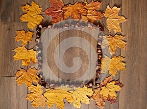 Abstract frame on a brown wooden background with the use of autumn yellow leaves