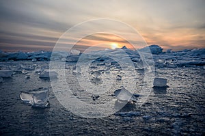 Abstract frozen winter sunrise seascape with ice and colored the sky.