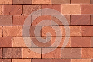 Abstract full-frame close-up of a wall of brown, terracotta-colored, and reddish rectangular bricks, showcasing their