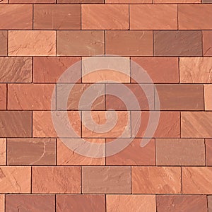 Abstract full-frame close-up of a wall of brown, terracotta-colored, and reddish rectangular bricks, showcasing their