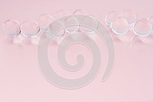 Abstract gentle pink background -  transparent glass balls in a row on pastel color, copy space.