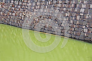 Abstract geometric background with green water and gray brick wa