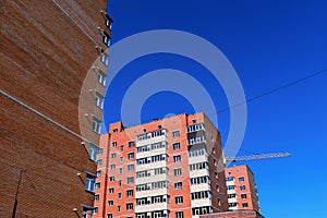 Abstract geometric construction template with new high-rise buildings and tower crane isolated on blue sky background. Urban