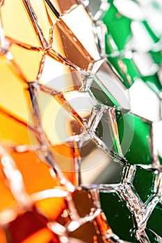 Abstract geometric pattern in orange, green, and clear glass reflections