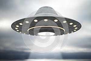 Abstract grey UFO flying in blurry dull sky with mockup place. Spaceship and science concept.