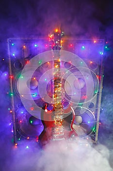 Abstract guitar with festive Christmas lights and music speakers in smoke