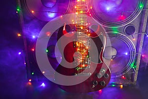 Abstract guitar with festive Christmas lights and music speakers in smoke