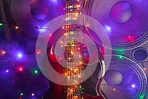 Abstract guitar with festive Christmas lights and music speakers in smoke