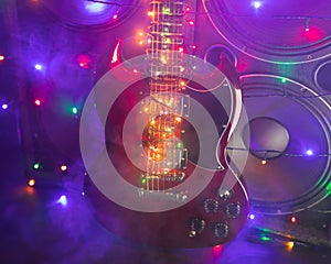 abstract guitar with festive Christmas lights and music speakers in smoke