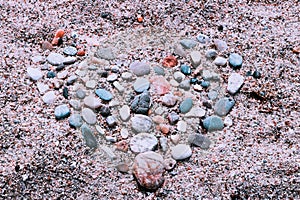 Abstract illustration of a heart made of stones at the sand.