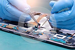 The abstract image of the asian technician assembling inside of tablet by screwdriver in the lab.